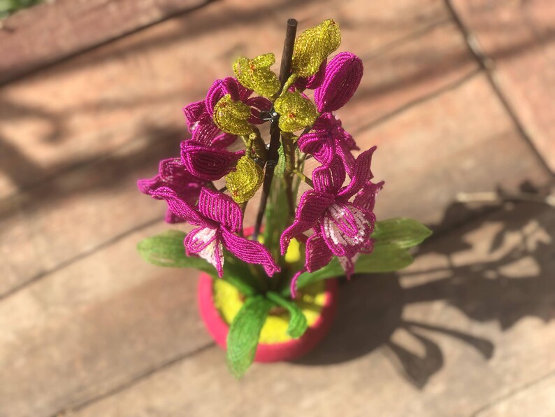 Orchidée en perles magenta dans un pot rose, art floral fait main